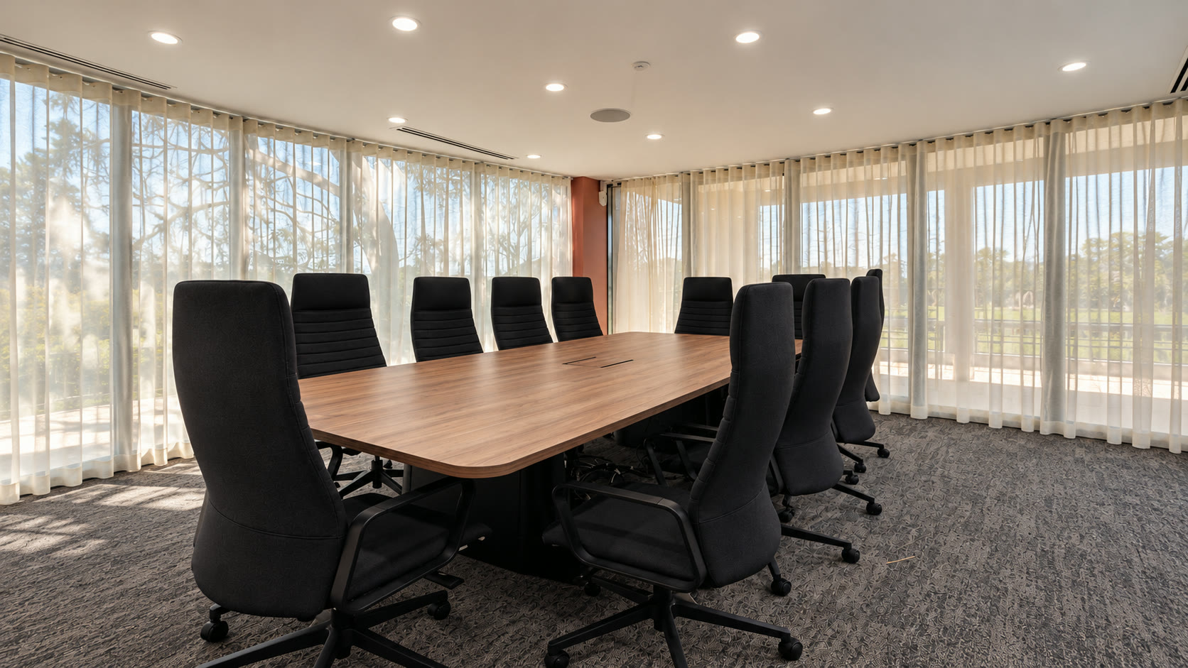 Tradie Hubb meeting room in Kirrawee with a long timber table, chairs and daylight through sheer curtains