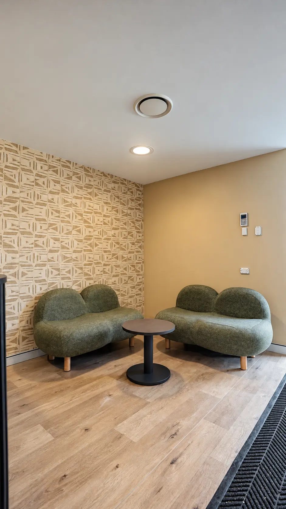 Lounge corner with two green sofas and a small round table